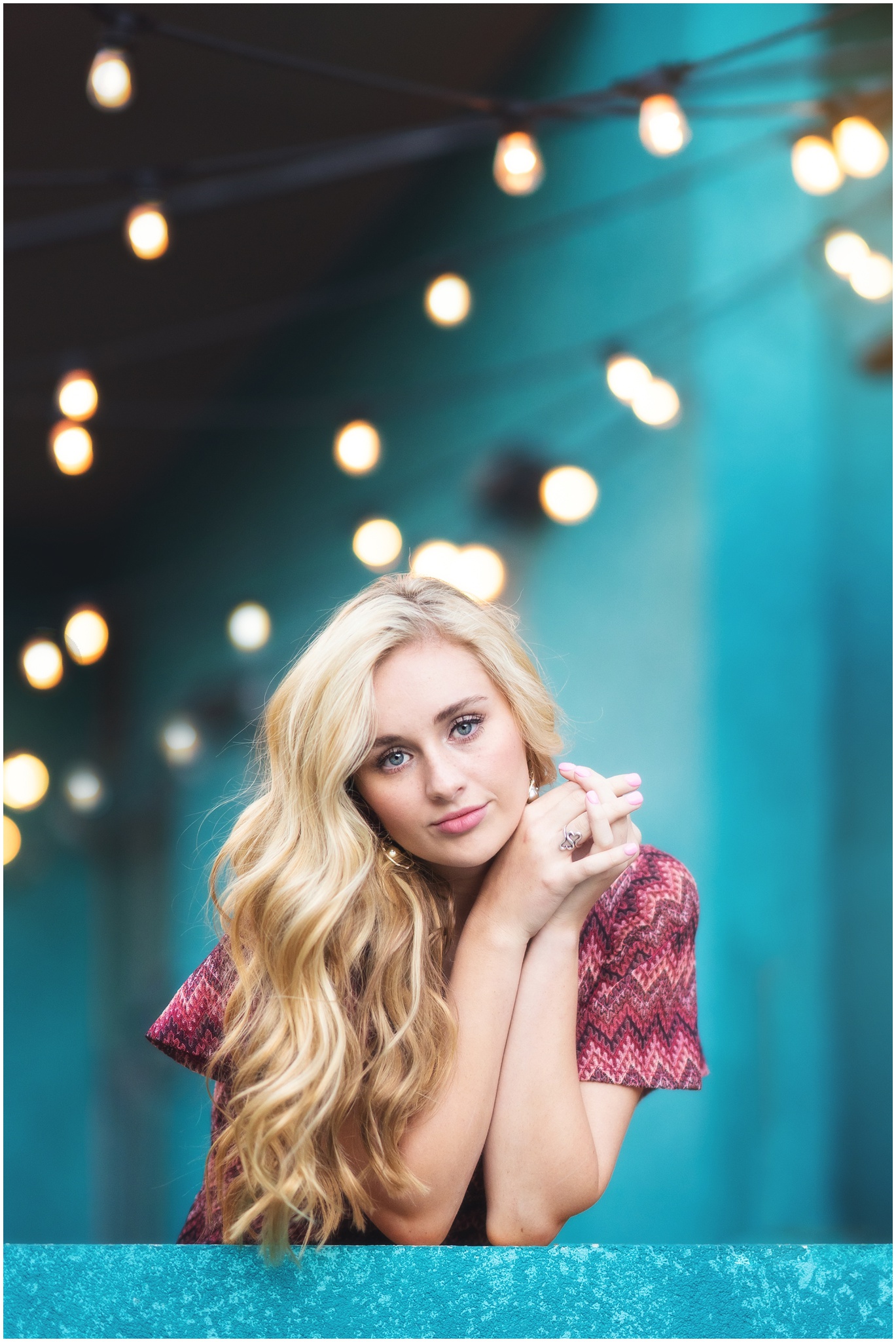 blond girl leaning on elbows with sparkle lights behind